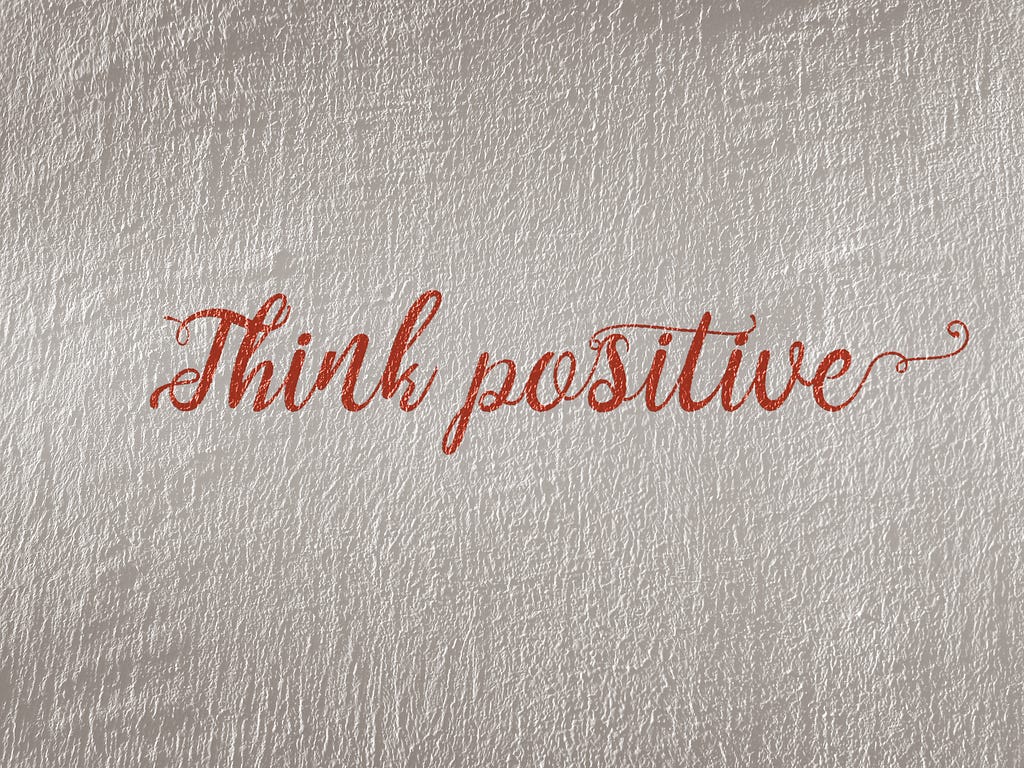 A piece of paper with the words “think positive” written in red ink.