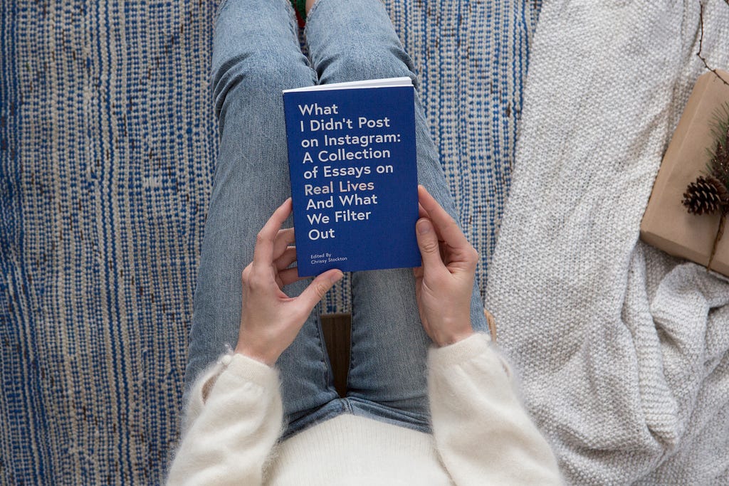 An image of a book on a woman’s lap that says “What I Didn’t Post on Instagram”