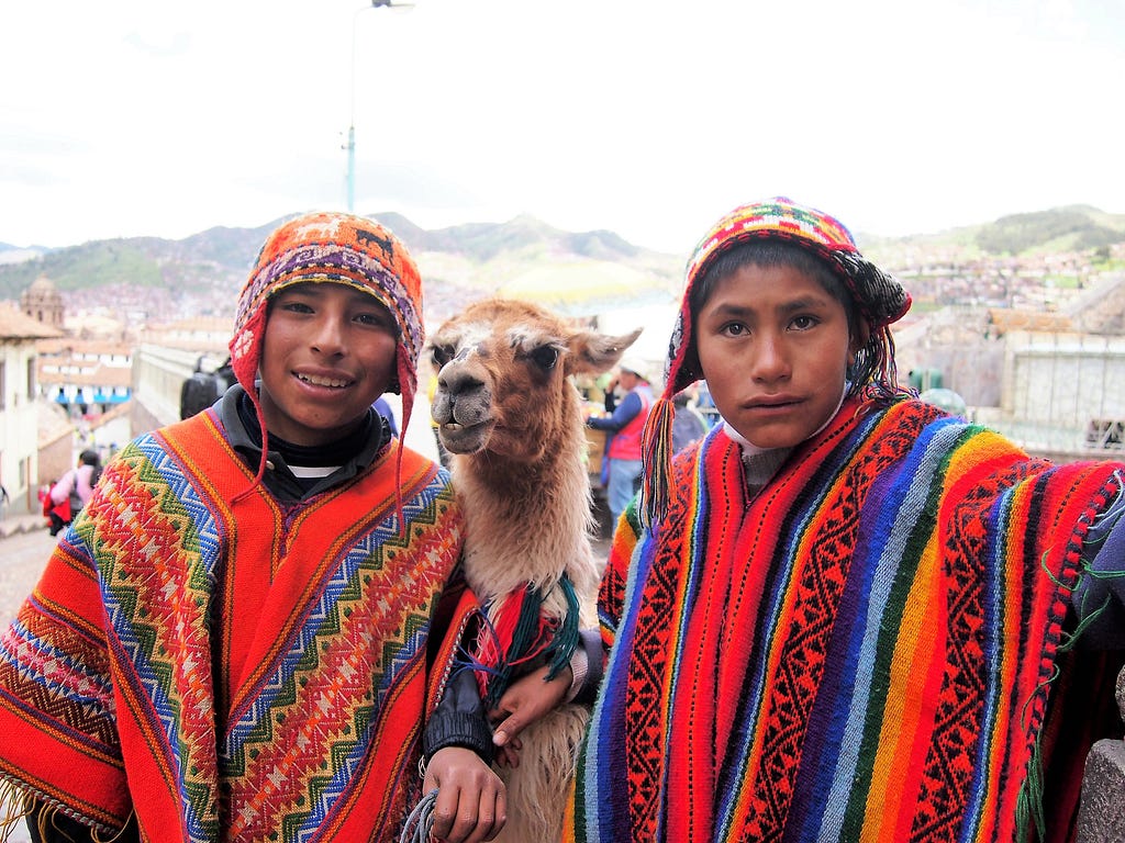 Two local kids posing with an alpaca in Cusco, Peru