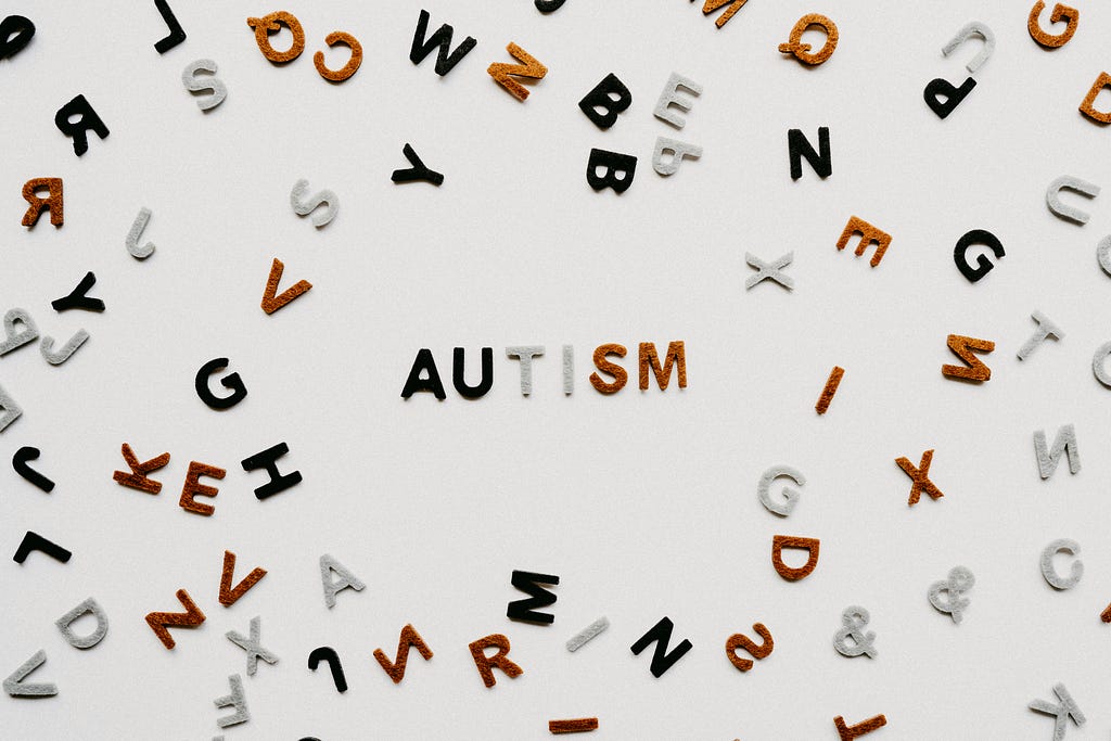 A white background with letters haphazardly displayed and the word AUTISM in the middle.