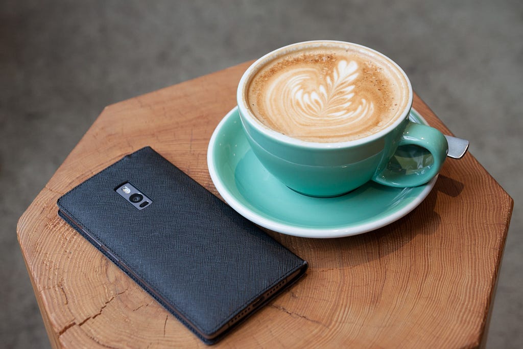 Phone in case and latte on a small coffee table / Photographer: Kim S. Ly | Source: Unsplash