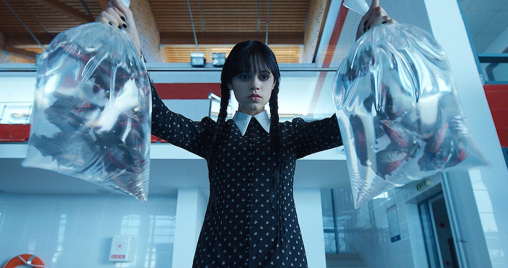 Wednesday Addams holding two bags of piranhas