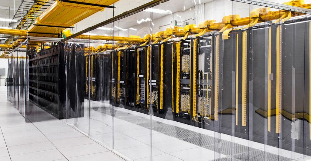 A data center in Iowa, owned by Google, showing racks of hundreds of computers arranged neatly in yellow shelves.