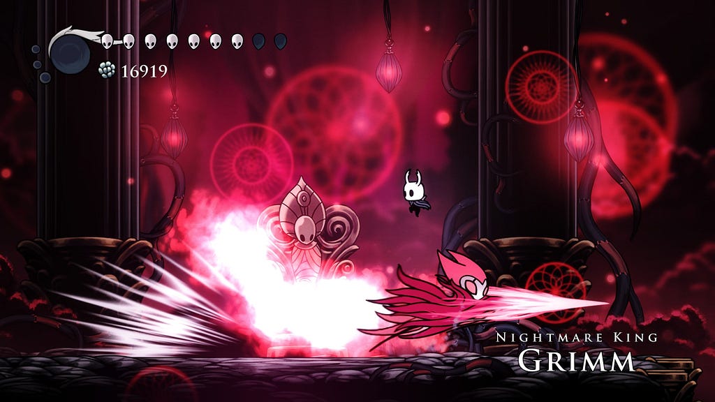 Nightmare King Grimm, bright red and covered in red flames, charges across the bottom of the screen. The player jumps over him.