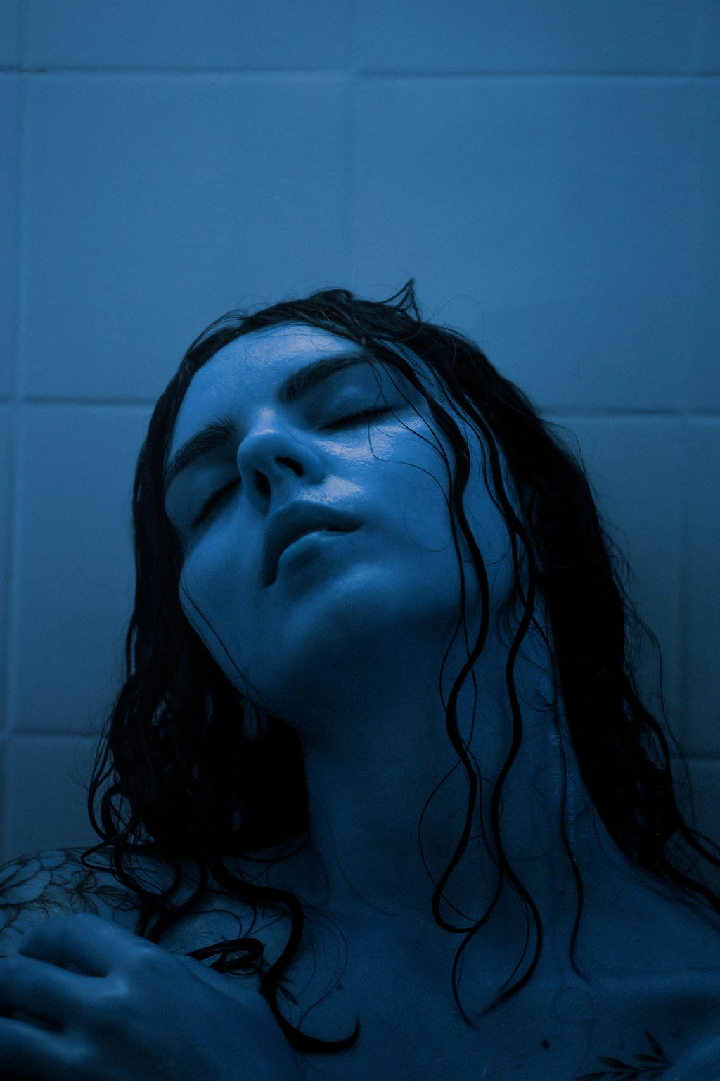 A girl closing eyes while in shower.