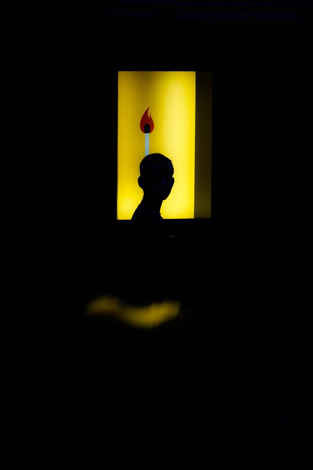 A silhouette of a person, backlit by an illuminated sign.