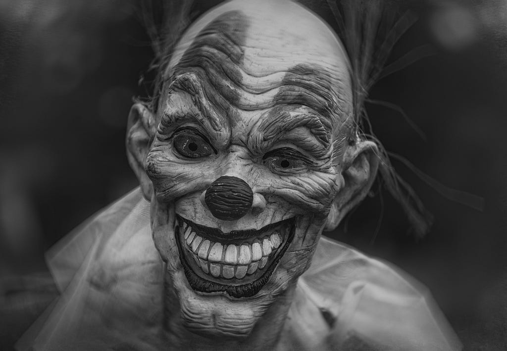 horrifying scary clown grinning at the camera