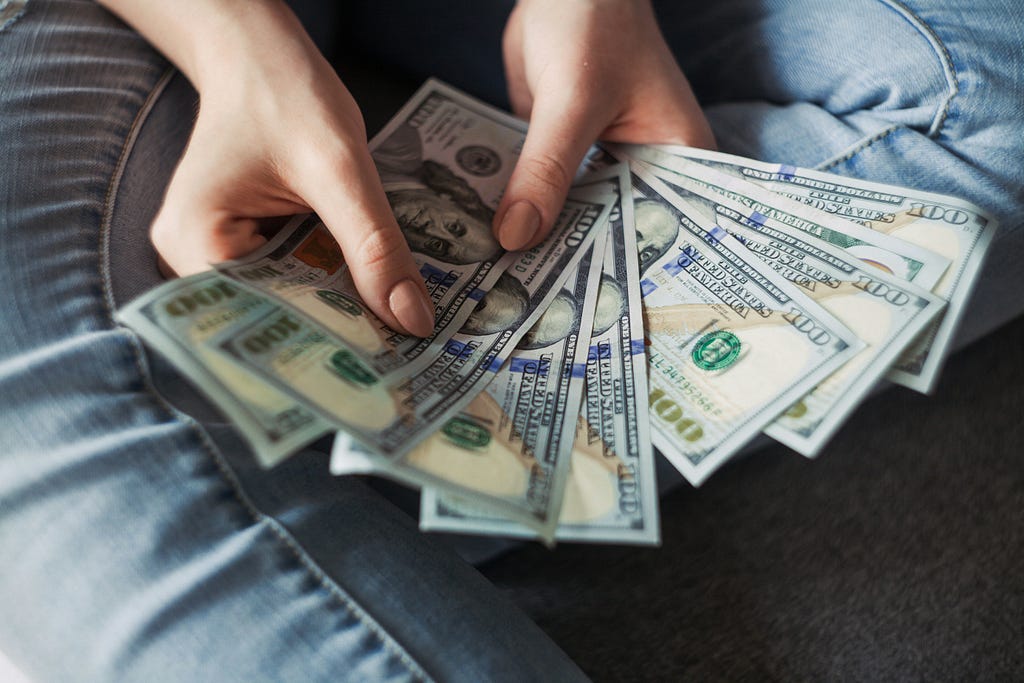 a person holding a handful of bank notes