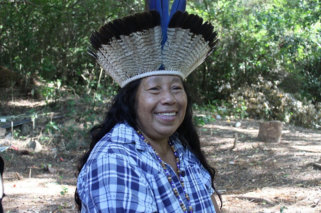 A cacica Gah Té, com colar e cocar, em meio às árvores da Retomada. Foto: