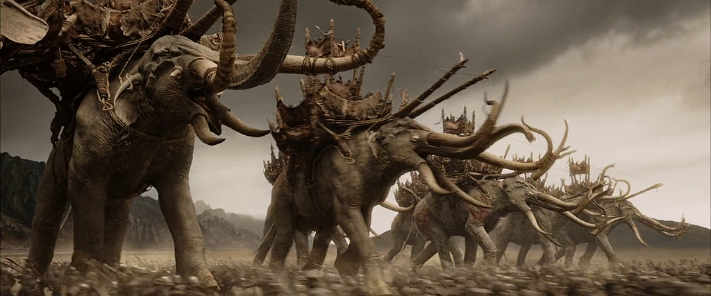 Elefantes gigantes cheios de presas e com cabines no dorso avançam sobre um exército. Cena do filme O Senhor dos Anéis: O Retorno do Rei