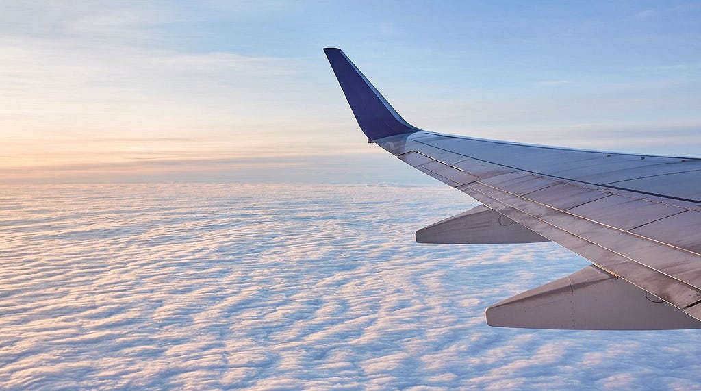 Airplane wing above clouds at sunrise