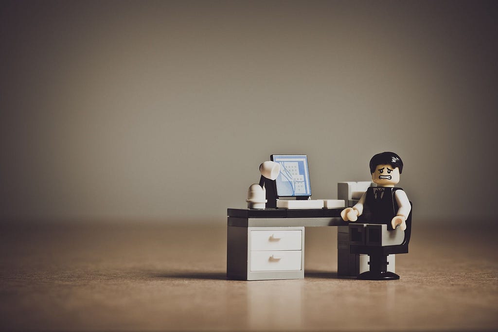 A Lego™ piece man with a stressed expression at a desk.