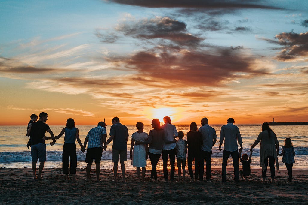 a big family watching the sunset on a beach