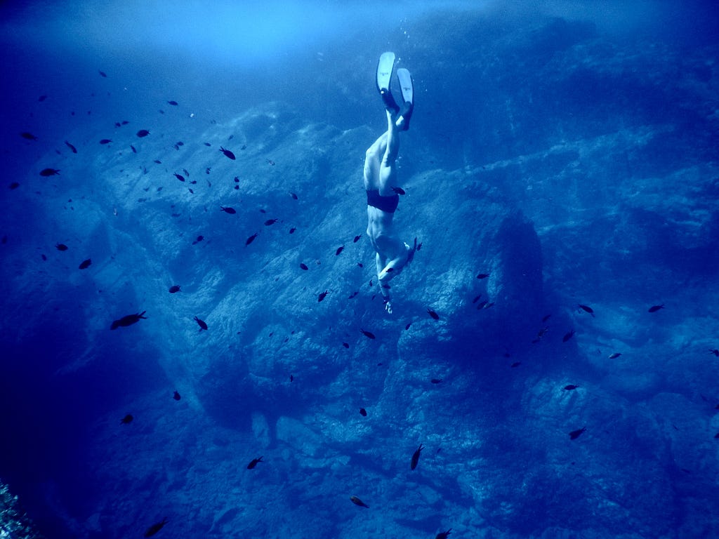 Person diving in the deep blue sea