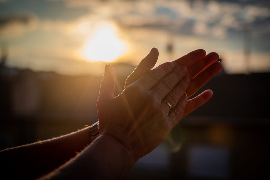 A lovely picture of someone clapping with the sun behind them.