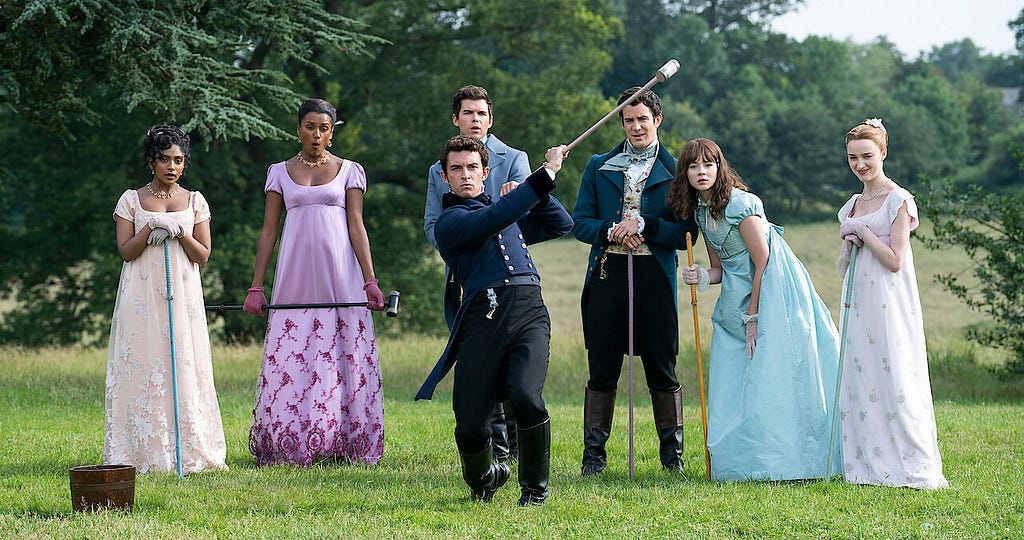 An image shows the characters from Bridgerton Season 2 playing pall mall. They are in period clothing and watch as Anthony Bridgerton hits the ball.