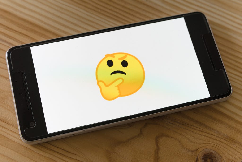 A phone screen with a “thinking” emoji on it