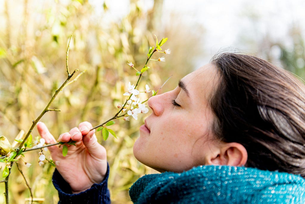 This image depicts a woman smelling a flower.