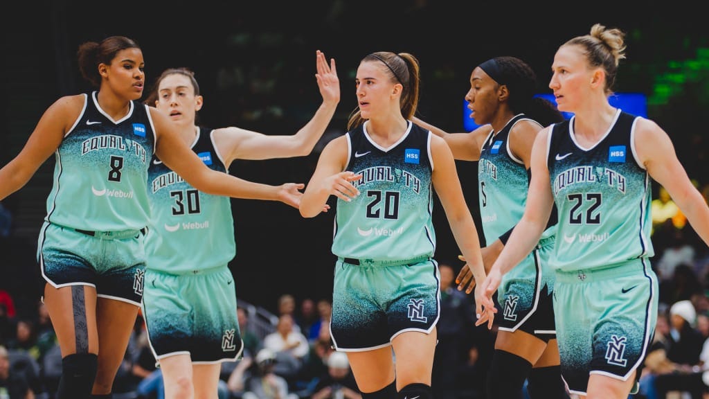 The New York Liberty team including (left to right) Nyara Sabally, Breanna Stewart, Sabrina Ionescu, Kayla Thornton, and Courtney Vandersloot, celebrate by giving each other high fives.