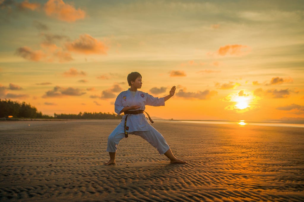 a man performing karate infront of rising sun