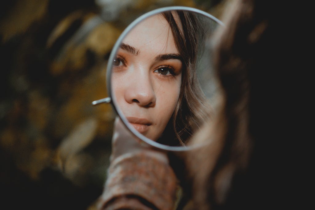 Girl looking at herself in a round mirror