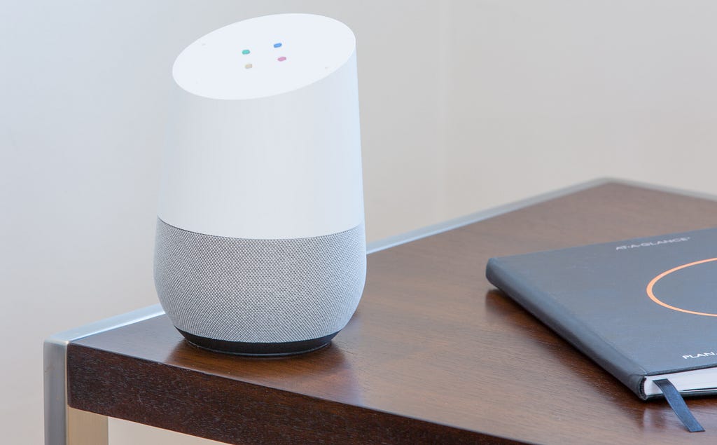 A Google Home sitting on a wooden table.
