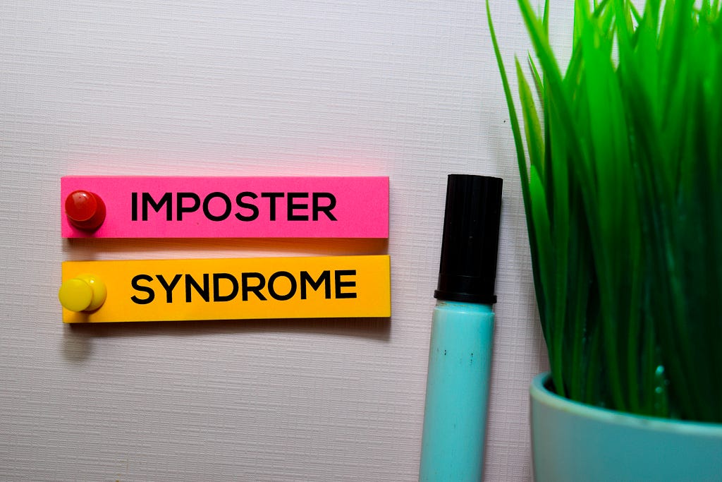 Imposter Syndrome text on sticky notes isolated on office desk