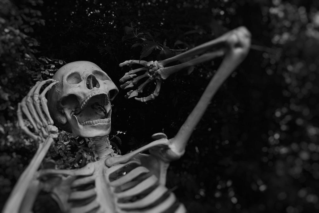 A black-and-white photo of a skeleton screaming, its hands hoovering beside its face.