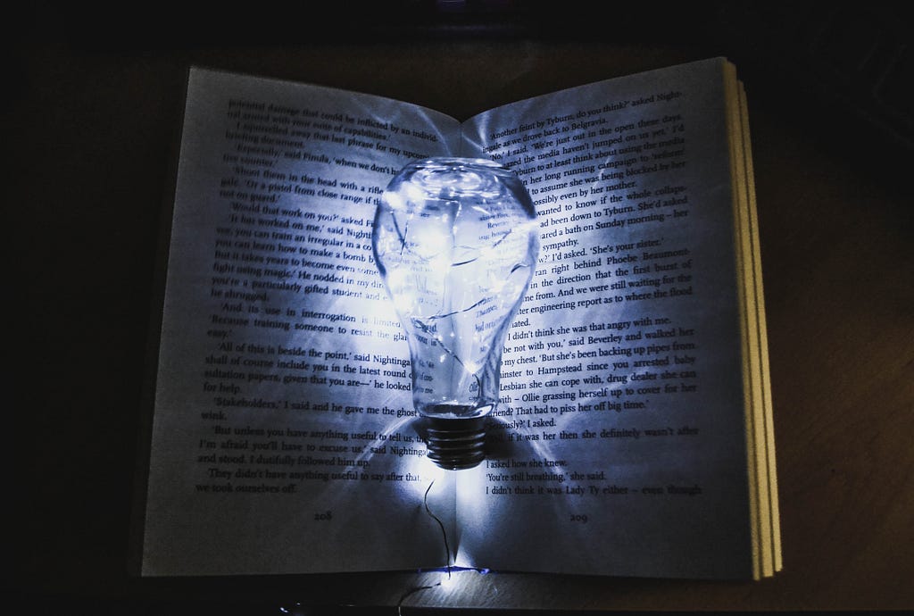 A glowing clear light bulb resting in a darkened book