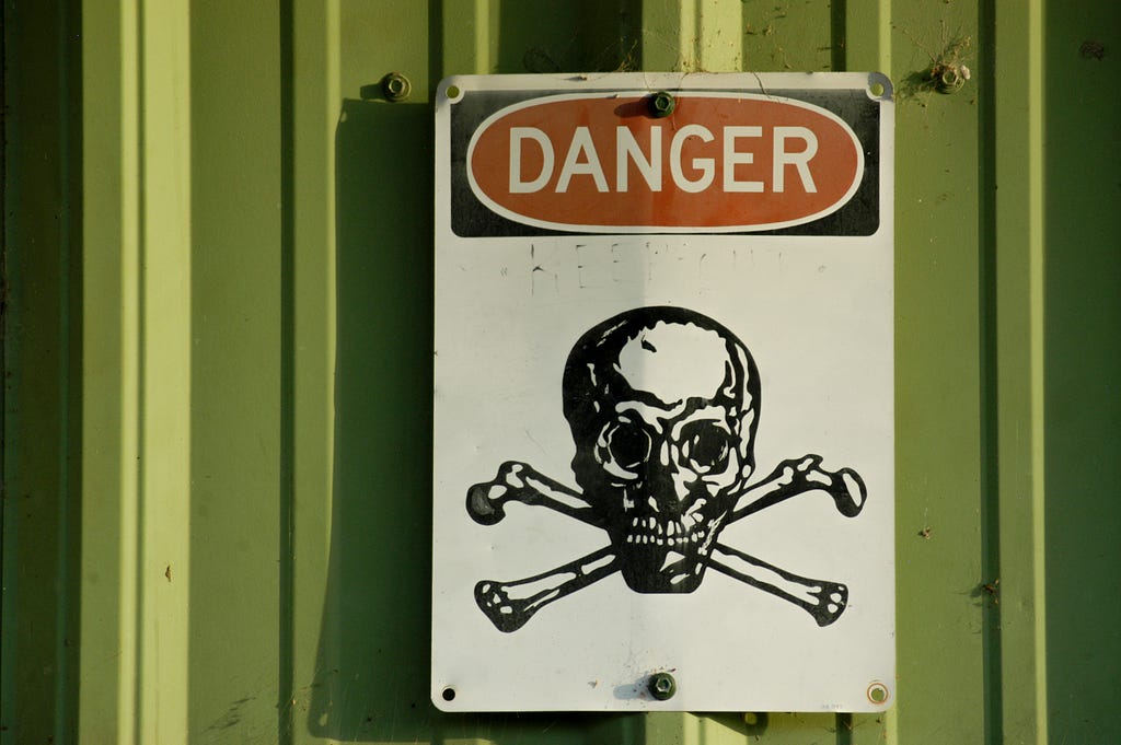 Danger sign wtih skeleton head on green background