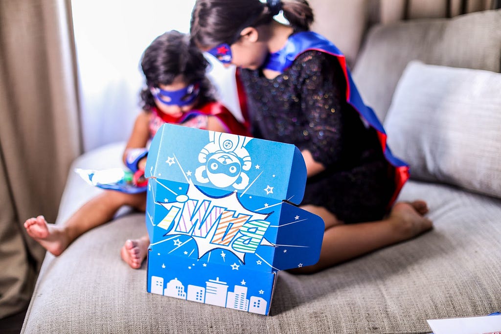 Two children wearing masks play with a Together We Rise superhero kit