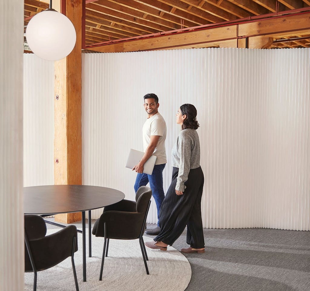 Two employees walk through a room in the Faire office.