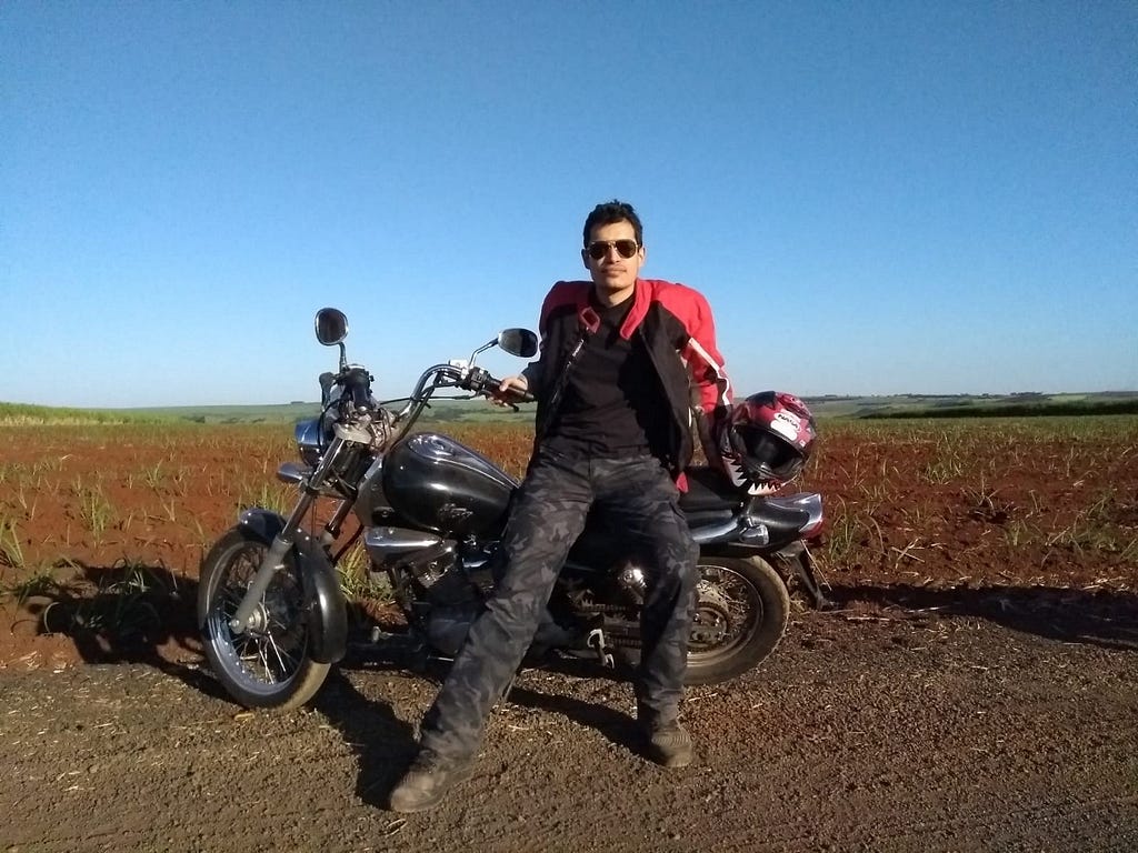 Eu de jaqueta, sentado na moto, com a linha do orizonte atrás