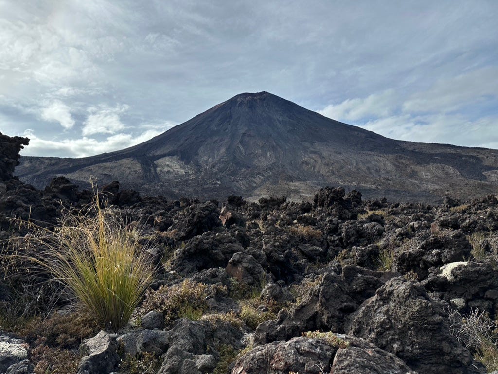 Volcano with rocks and shrubs in foreground.