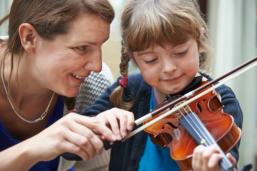 Teacher helping young female pupil in a violin lesson.