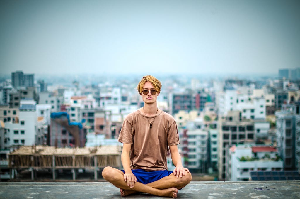 A man meditating on the rooftop of a tall building