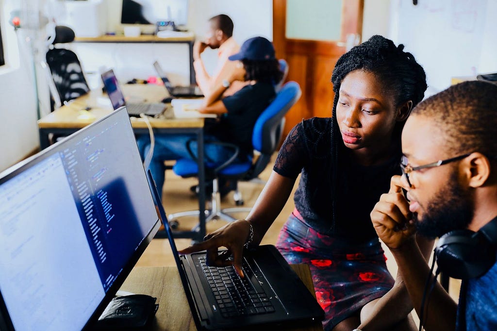 Two people sitting next to each other and looking at a computer screen together