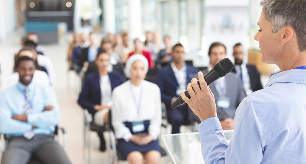 Female mentor giving motivational speech at business conference