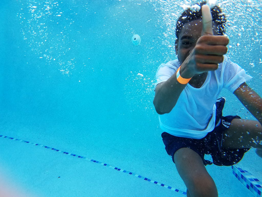 Child giving thumbs up signal underwater