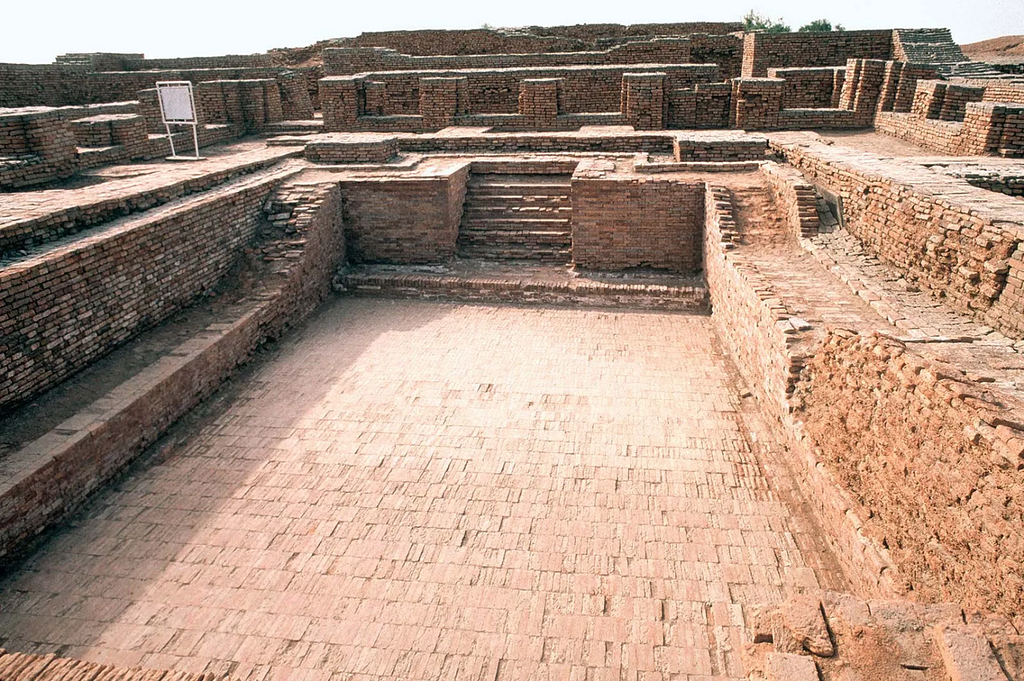 The Great Bath of Mohenjo-daro, an ancient brick-lined water tank from the Indus Valley Civilization. The structure features steps leading down into the pool, surrounded by ruins of old brick walls, showcasing advanced urban planning from around 2500 BCE