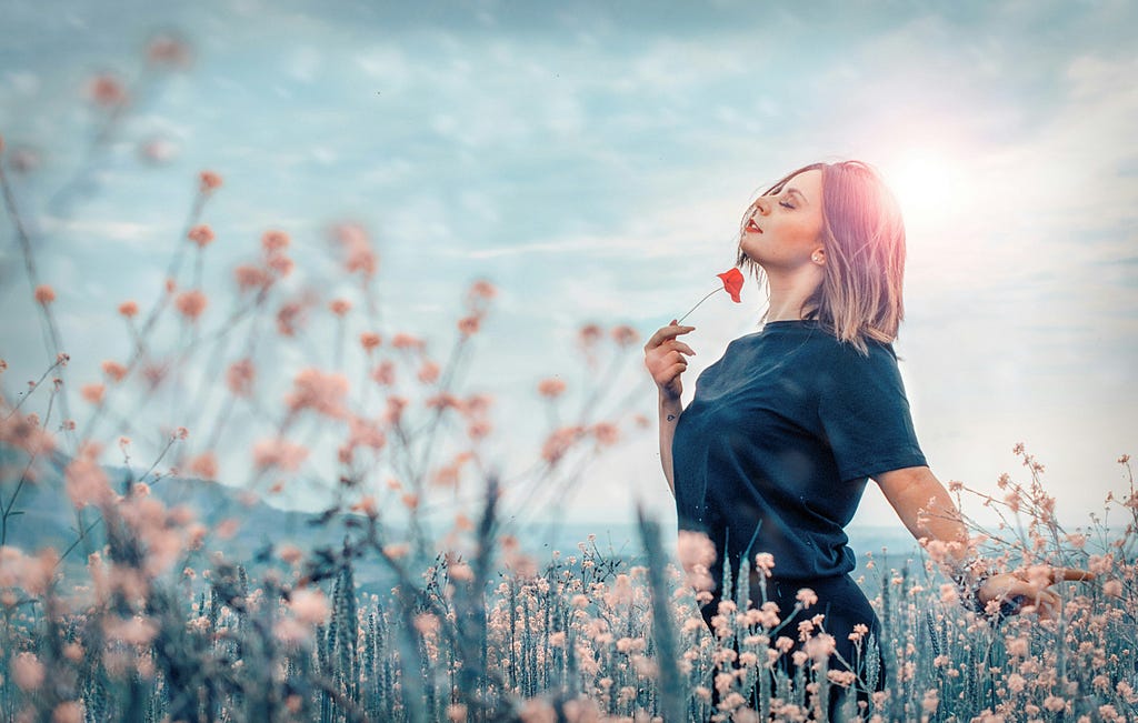 A woman in a field of flowers, she looks relaxed and content.