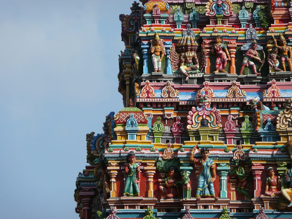 Picture of an entrance tower in a Hindu temple sporting sculptures of deities and mythical beings