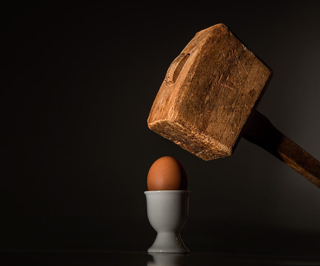 Massive wooden mallet over an egg