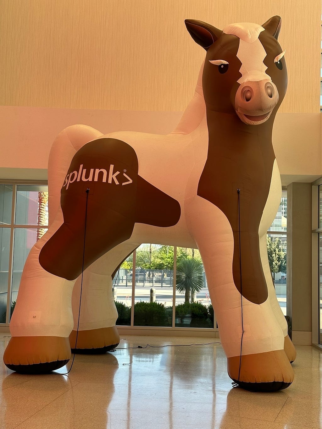 A large inflatable horse with the word Splunk on its side is displayed in a well-lit indoor area with windows in the background.
