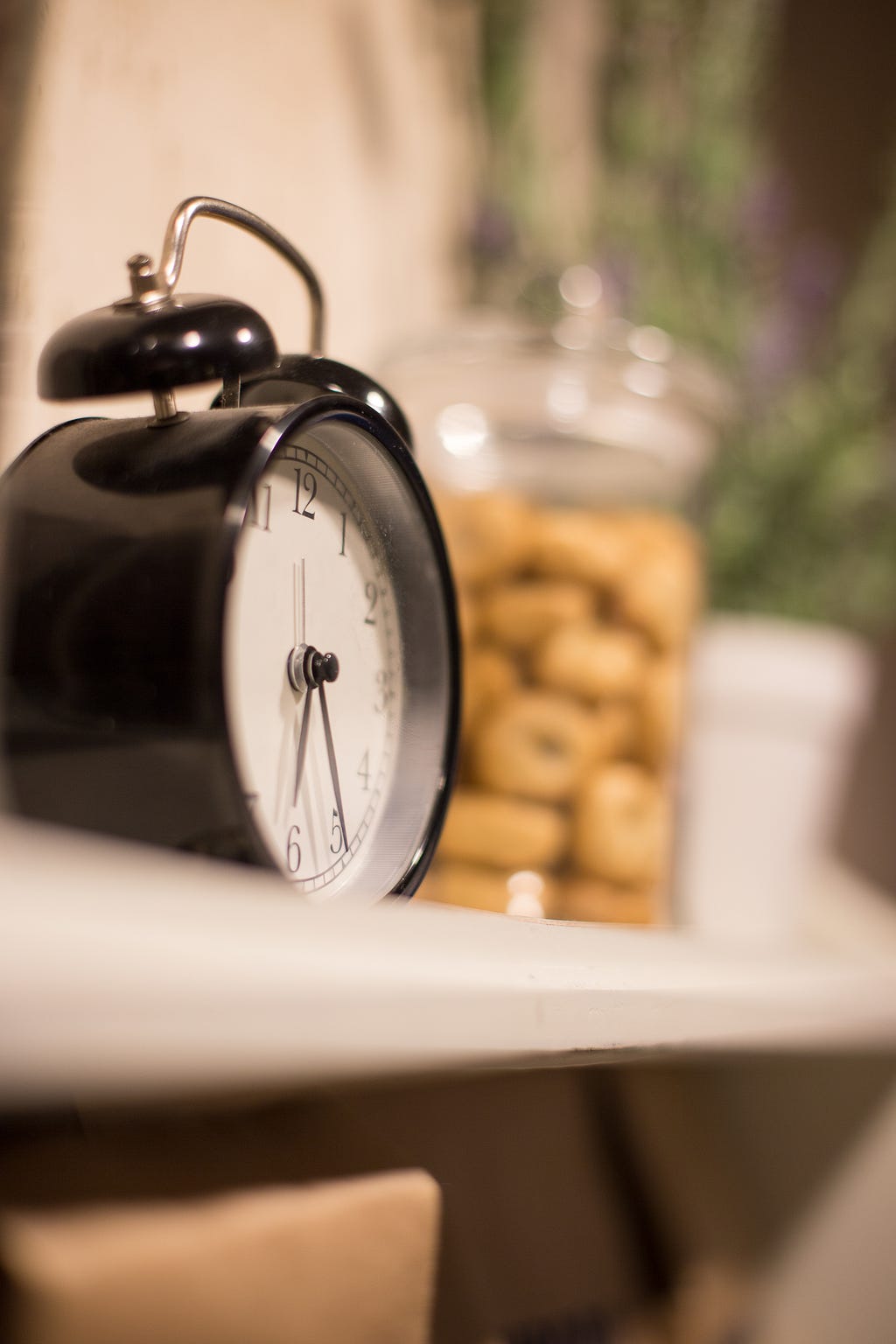 An alarm clock beside a jar of cookies