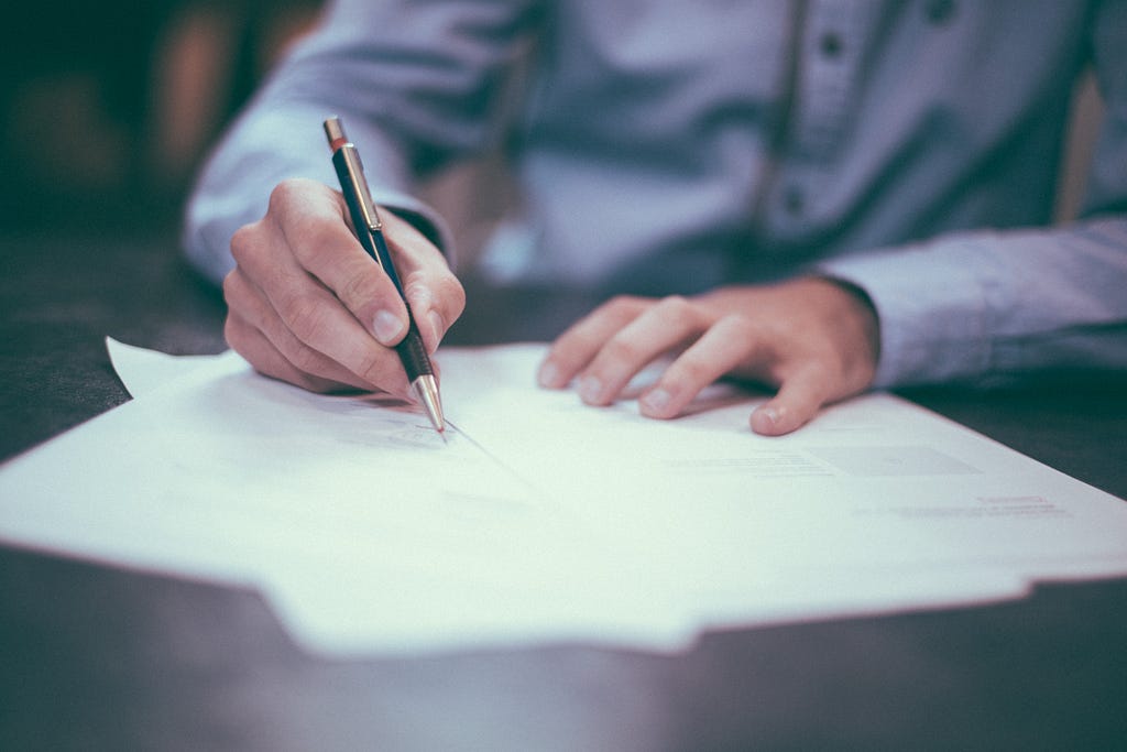 Person signing contract on paper