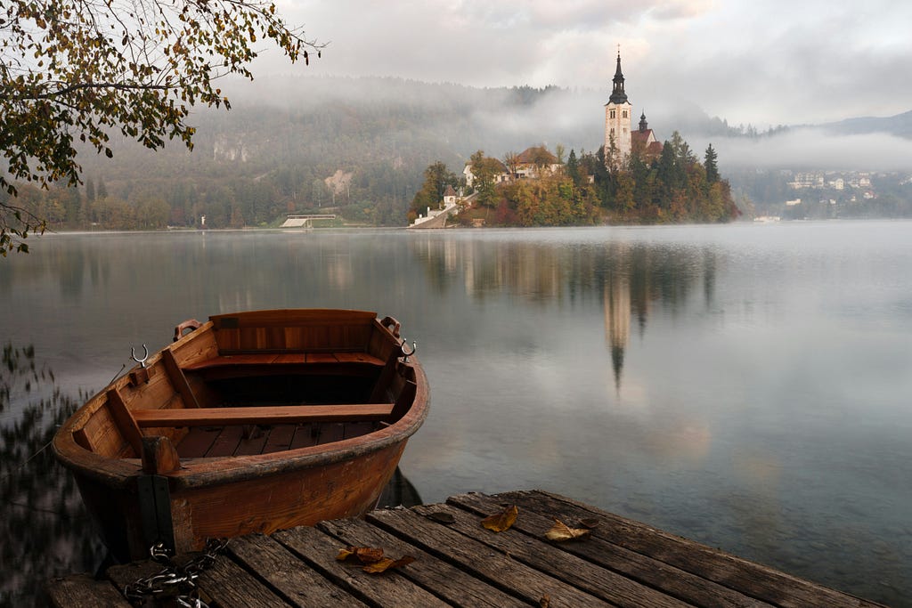 Boat by a lake, misty day, with a castle across the lake