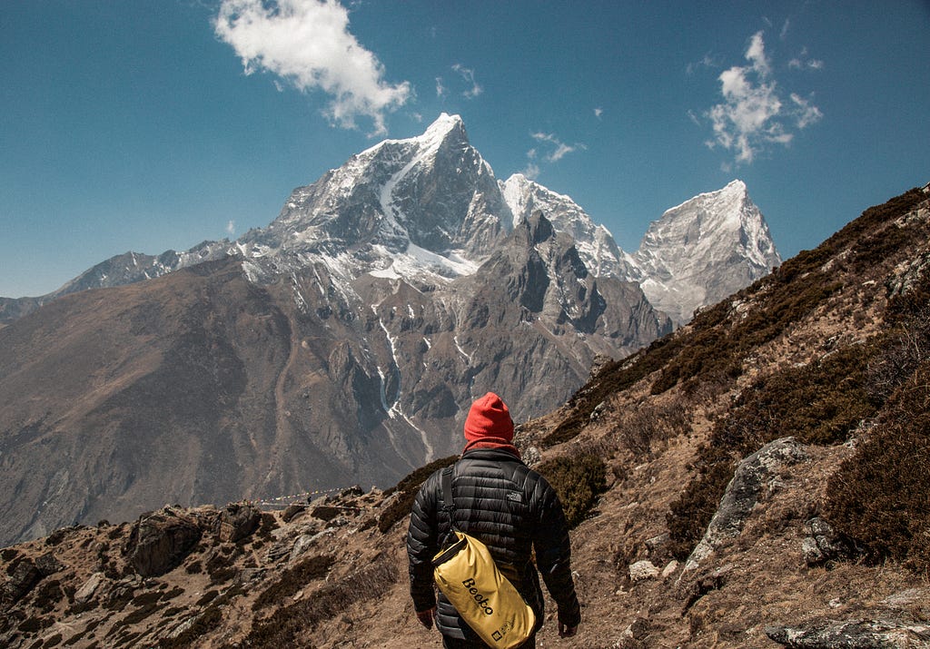 A man scaling up a mountain that seems so near and yet so fay