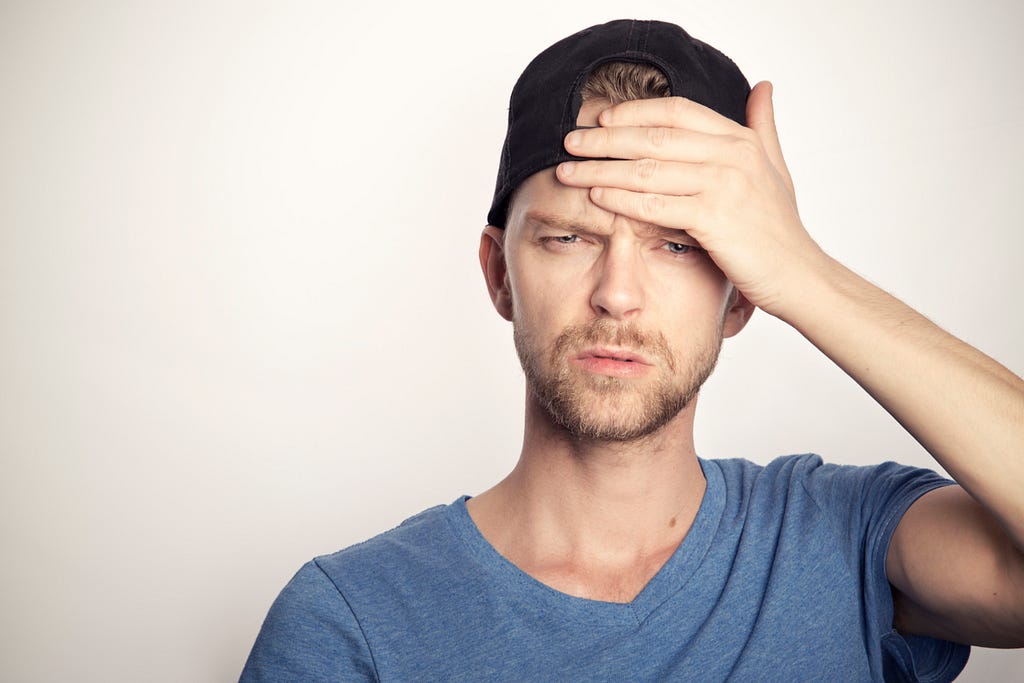 Confused looking man with hand on his head.