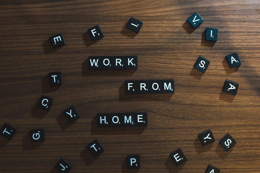 Scrabble letters on a table. They spell out “Work from home.”